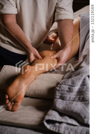 Massage therapy session focusing on relaxation and muscle relief in a serene spa environment, showcasing skilled hands working on a client's leg 132119169