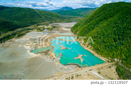 The effects of pollution on a natural habitat, featuring damaged terrain and pools of toxic water surrounded by lush hills. The effects of pollution on a natural habitat, featuring damaged terrain and pools of toxic water surrounded by lush hills. 132119507