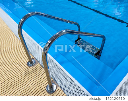 Swimming pool with stair and water. Swimming pool with handrail. Stainless steel ladder in pool. Grab bars ladder in the blue swimming pool 132120610