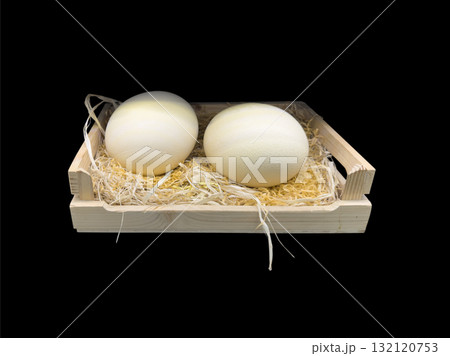Two ostrich egg in wooden plate isolated on black background. Big ostrich egg 132120753