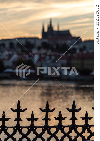 Silhouette of a fence with blurred Vltava river and Prague castle at sunset in Prague, Czech Republic Silhouette of a fence with blurred Vltava river and Prague castle at sunset in Prague, Czech Republic 132122632