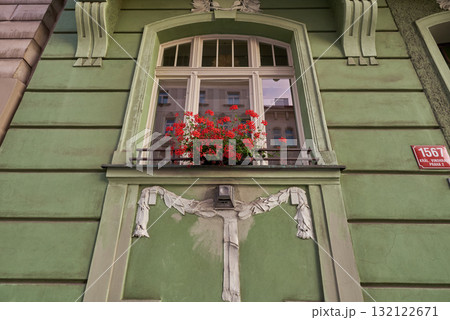 A green building facade with a decorative window and red flowers in historic Vinohrady district in Prague, Czech Republic A green building facade with a decorative window and red flowers in historic Vinohrady district in Prague, Czech Republic 132122671