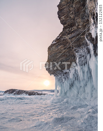 Dramatic ice formations contrast against rugged cliffs in a winter landscape at dawn 132122685
