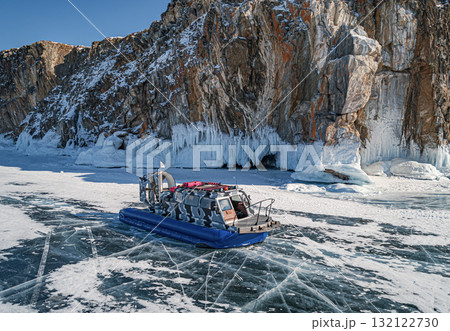 Hovercraft parked on a blue cracked ice of the lake Baikal. Tourists transportation and entertainment on winter Baikal. Hovercraft parked on a blue cracked ice of the lake Baikal. Tourists transportation and entertainment on winter Baikal. 132122730