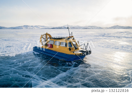Aerial view on a hovercraft parked on the beautiful cracked ice of the lake Baikal. Winter Baikal, frozen lake. Amazing winter landscape. 132122816