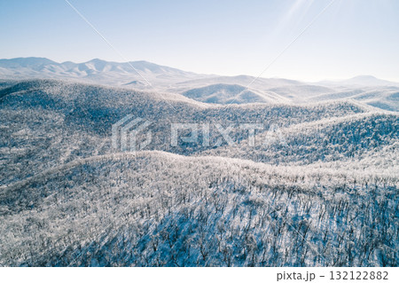 Aerial view of a snow-covered mountain landscape under clear blue sky in winter season Aerial view of a snow-covered mountain landscape under clear blue sky in winter season 132122882