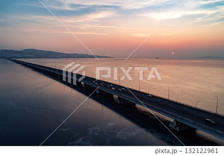 Aerial drone view of low-water bridge across the bay with moving car during the sunset. Active movement of transport cars vehicles in different directions. 132122961