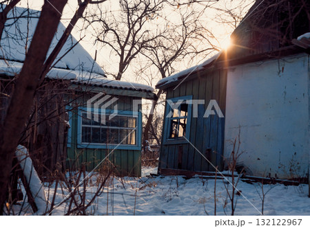 Winter sunset illuminating abandoned buildings in a rural setting with snow-covered ground. Winter sunset illuminating abandoned buildings in a rural setting with snow-covered ground. 132122967