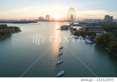 Sunset view over the river with a ferris wheel and sailboats in the foreground Sunset view over the river with a ferris wheel and sailboats in the foreground 132122975