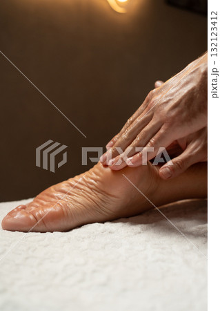 Close-up of a foot massage in a spa, therapist gently massaging the heel with oil, relaxation and wellness concept, warm light atmosphere, skin care and body therapy. Close-up of a foot massage in a spa, therapist gently massaging the heel with oil, relaxation and wellness concept, warm light atmosphere, skin care and body therapy. 132123412
