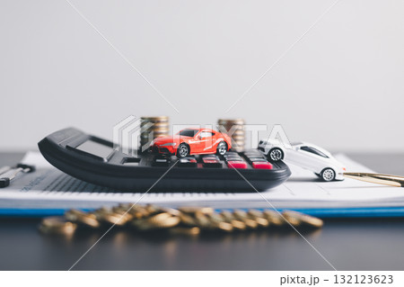 Red and white car models with open doors positioned beside stacked coins, symbolizing car loan, auto finance, insurance, investment, wealth, savings and money management concept. 132123623