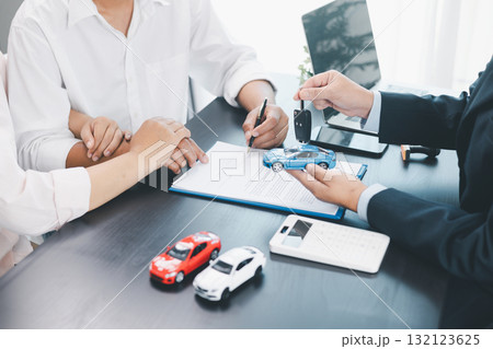 Customer receiving car key from dealer after signing contract, successful auto purchase and finance agreement at office desk, concept of vehicle loan, leasing, insurance or ownership. vehicle loan. Customer receiving car key from dealer after signing contract, successful auto purchase and finance agreement at office desk, concept of vehicle loan, leasing, insurance or ownership. vehicle loan. 132123625