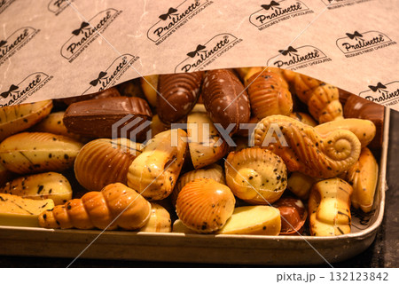 Assorted Belgian chocolate pralines in various shapes under branded paper in Bruges, Belgium 132123842