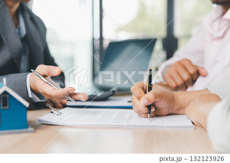 Close up of business people signing loan agreement contract with pen and paperwork on desk, financial deal concept with laptop and calculator in modern office environment. loan agreement contract. 132123926