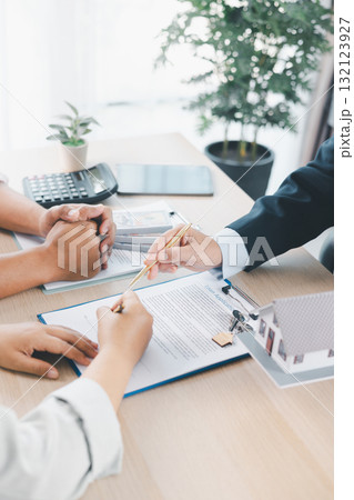 Close up of business people signing loan agreement contract with pen and paperwork on desk, financial deal concept with laptop and calculator in modern office environment. loan agreement contract. 132123927