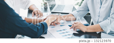 Panorama of business teamwork success with three people join hands over financial documents, symbolizing partnership, trust, corporate collaboration, achievement and positive workplace culture. 132123970