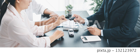 Panorama view of car dealer handing key and vehicle model to customer during contract signing, concept of auto loan, finance, leasing, insurance, purchase agreement and business success. auto loan. 132123972