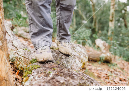 Close up of hiker walking on tree trunk in forest, symbol of adventure, exploration, balance, outdoor lifestyle, trekking, challenge and journey through nature with hiking boots. hiking adventure 132124093