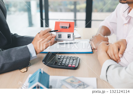 Close up of real estate agent showing small house model to client with calculator, contract paperwork on desk, concept of mortgage loan, home ownership, property investment agreement. mortgage loan Close up of real estate agent showing small house model to client with calculator, contract paperwork on desk, concept of mortgage loan, home ownership, property investment agreement. mortgage loan 132124114
