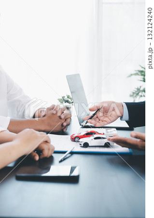 Car loan officer explaining contract details to customer with cash, calculator, key and toy car on table, concept of auto finance, leasing, insurance, payment plan and business agreement. car loan. 132124240