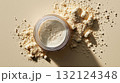Scattered beige powder and clear jar on pastel background in natural light, symbolizing beauty or supplement concept 132124348