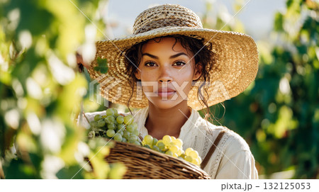Young woman with straw hat harvesting green grapes in sunny vineyard 132125053