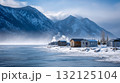 Ice fishing village on a frozen lake, small wooden huts, smoke rising, framed by snowy mountains. Life in permafrost conditions, climate change problems on the planet. Global warming 132125104