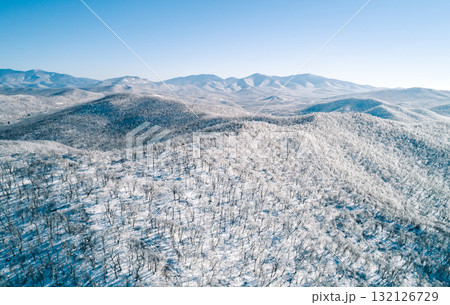 Aerial view of a snow-covered mountain landscape under clear blue sky in winter season Aerial view of a snow-covered mountain landscape under clear blue sky in winter season 132126729