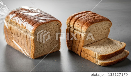 Fresh whole wheat sliced bread, one loaf packaged and another unwrapped on a table 132127179