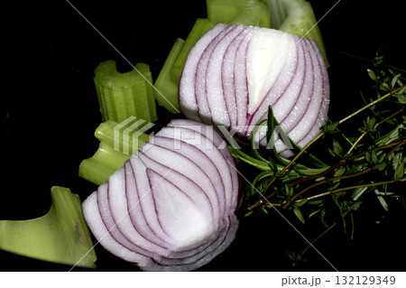 Close up of chopped celery onion and rosemary waiting to be used to cook dinner on a black background 132129349