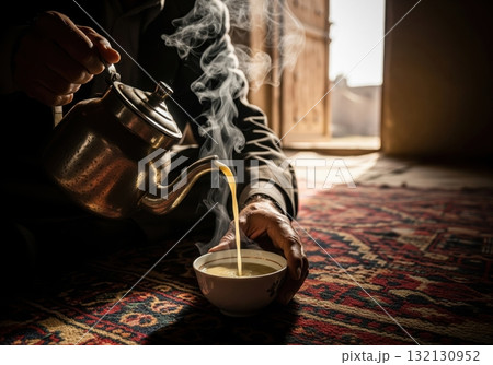 Man pouring traditional afghan qaymaq chai from a vintage teapot in a gesture of hospitality Man pouring traditional afghan qaymaq chai from a vintage teapot in a gesture of hospitality 132130952