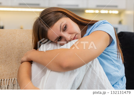 Young woman curls up arms around legs sad stressed after bad day seeks comfort silent and calm peace Young woman curls up arms around legs sad stressed after bad day seeks comfort silent and calm peace 132131479
