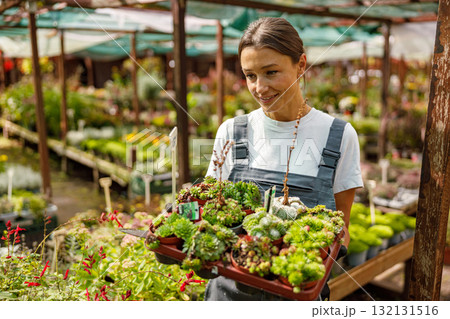 A joyful woman selecting beautiful succulents in a vibrant, greenfilled greenhouse 132131516