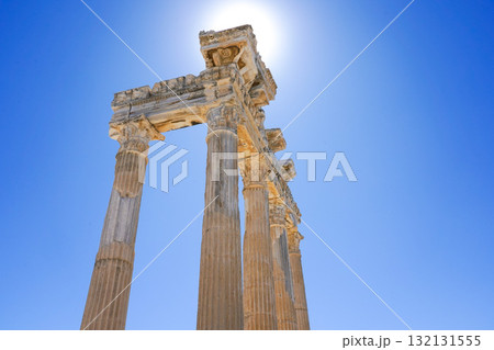 Majestic Ancient Pillars Bathed in Bright Sunlight Against a Clear Blue Sky, Highlighting Historical Architectural Grandeur 132131555