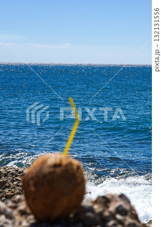 Refreshing Coconut Drink by the Sparkling Ocean Waves under a Clear Blue Sky, Perfect for a Tropical Escape and Summer Relaxation 132131556