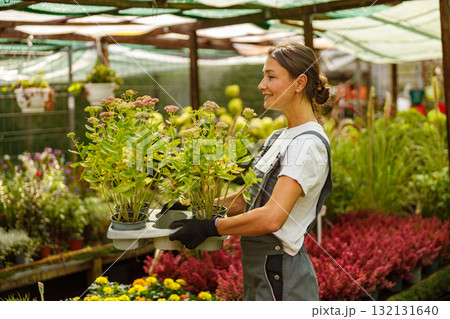 A Young Woman Engaged in Her Work at a Vibrant Garden Center Surrounded by Various Flower Pots 132131640