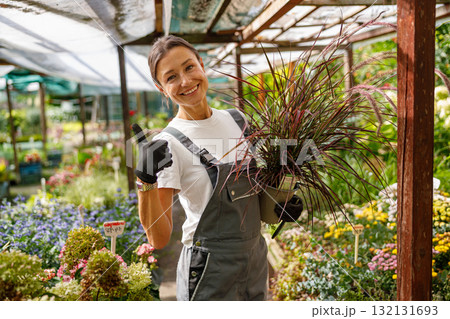 A Gardener is Smiling Happily with Beautiful Potted Plants in a Colorful Flower Nursery A Gardener is Smiling Happily with Beautiful Potted Plants in a Colorful Flower Nursery 132131693