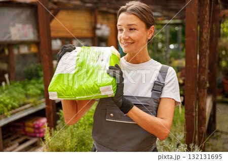 A Gardener Holding Fertilizer Inside a Greenhouse Dedicated to Caring for Plants and Their Growth 132131695