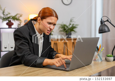 Young businesswoman frustrated laptop freezes hits table grabs head presses ctrl alt del for restart Young businesswoman frustrated laptop freezes hits table grabs head presses ctrl alt del for restart 132131697