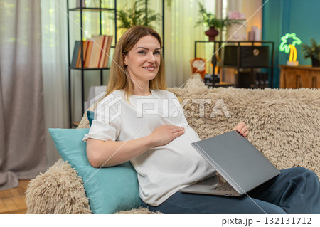 Pregnant woman closes laptop exhales relief smiles to camera rubs belly after finishing work shift Pregnant woman closes laptop exhales relief smiles to camera rubs belly after finishing work shift 132131712
