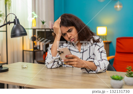 Indian woman upset after bad news on smartphone presses button places phone aside unhappy reaction 132131730
