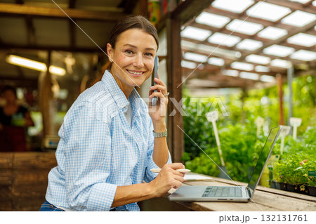 A Woman Skillfully Managing Various Work Tasks in a Greenhouse Environment Setting A Woman Skillfully Managing Various Work Tasks in a Greenhouse Environment Setting 132131761