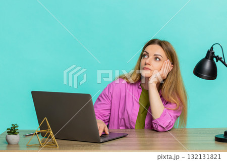 Adult woman working at laptop at table leaning on hand showing tired face and fatigue from long task 132131821