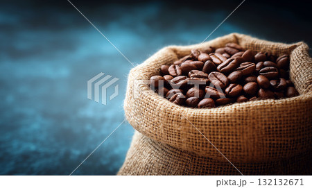 Close-up of roasted coffee beans in a burlap sack on a textured dark blue background, symbolizing aroma, freshness and energy Close-up of roasted coffee beans in a burlap sack on a textured dark blue background, symbolizing aroma, freshness and energy 132132671