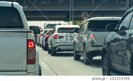 Rear side of white pickup car stop with turn on brake light. Cars lined up at traffic lights. There is a bridge over the intersection ahead. Traffic jam in the concrete road. Rear side of white pickup car stop with turn on brake light. Cars lined up at traffic lights. There is a bridge over the intersection ahead. Traffic jam in the concrete road. 132133348