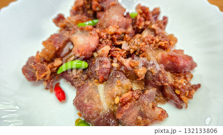 crispy fried pork with chili peppers on white plate close up crispy fried pork with chili peppers on white plate close up 132133806