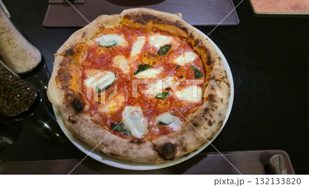 Margherita pizza with fresh mozzarella and basil on white plate in restaurant 132133820