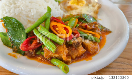 Thai Stir-Fried Pork Belly Crisp with Red Curry and Salted Egg served with rice on white plate Thai Stir-Fried Pork Belly Crisp with Red Curry and Salted Egg served with rice on white plate 132133860