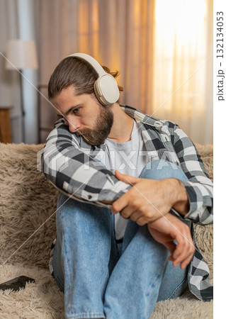 Man sad at home with headphones melancholic music track tearful mood quiet heartbreak divorce moment 132134053