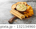 Deviled Egg Dip appetizer for a buffet or picnic with nachos, breadsticks and toast close-up on a wooden board. Horizontal 132134960